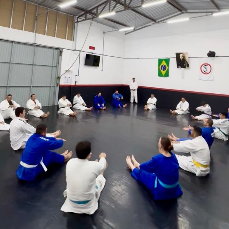 Turma adulta de judô sentada em roda durante o aquecimento